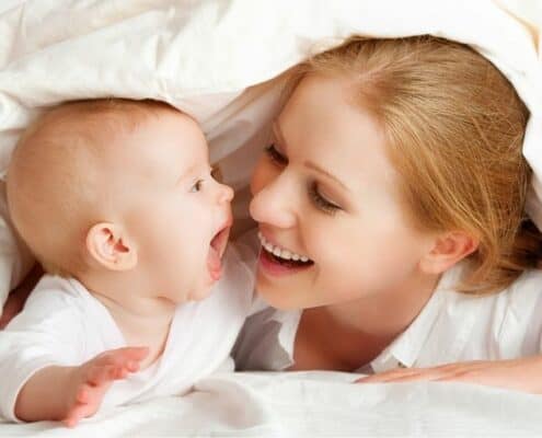 mother with newborn, under covers in bed, smiling