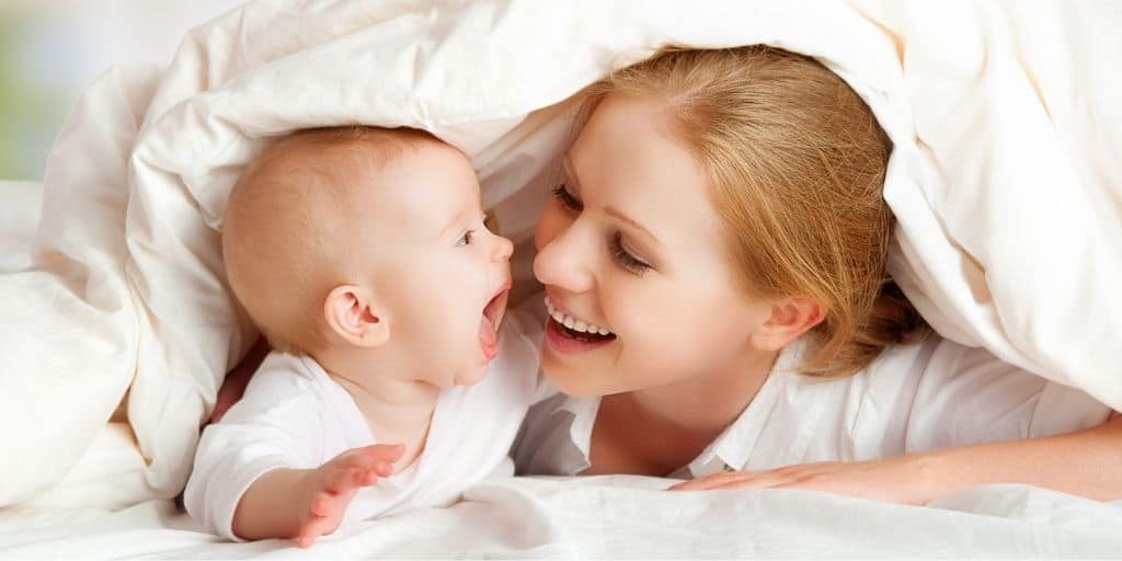 mother with newborn, under covers in bed, smiling