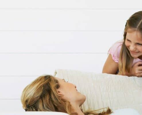 young teen talking with mom, who is laying on couch