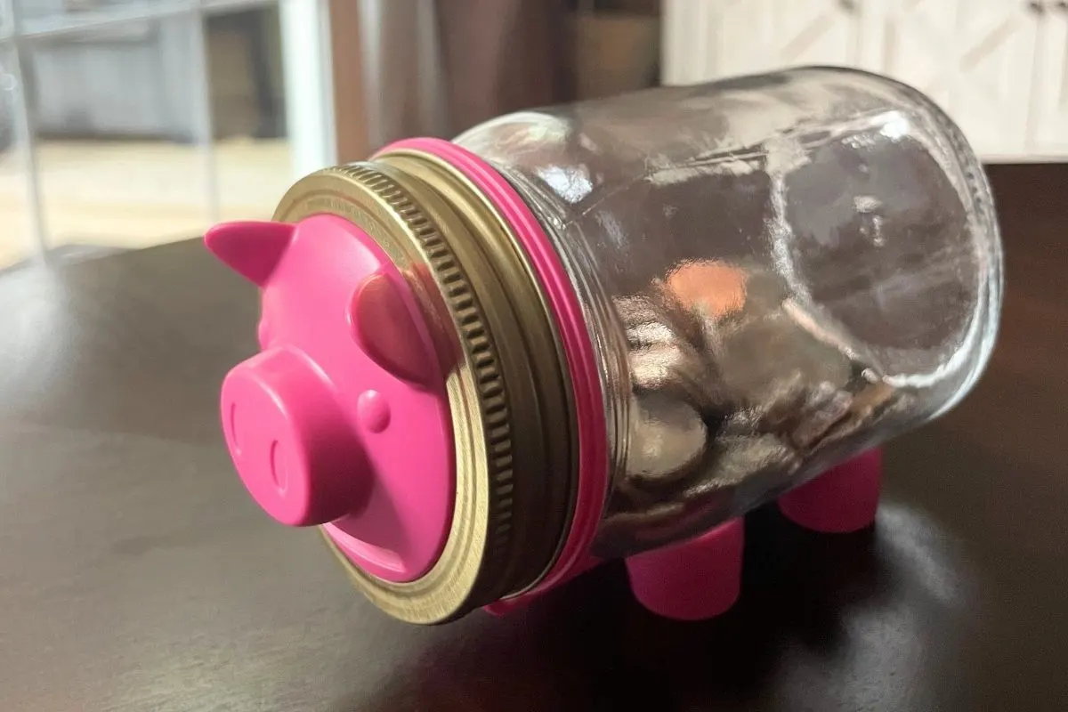 mason jar with money in it on its side, and piggy bank front and legs