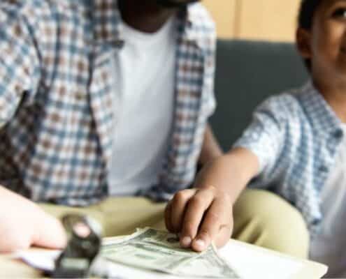 man with son in restaurant, letting son hand over money to waitress