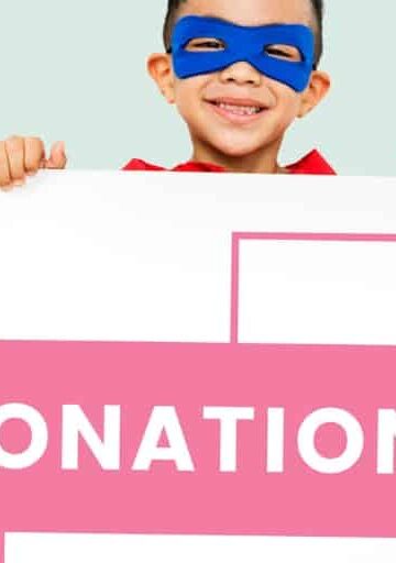 child with a blue superman mask on, holding a big envelope that says "donations"