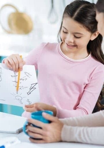 child with kid goal setting worksheet, pointing to it while showing to mother