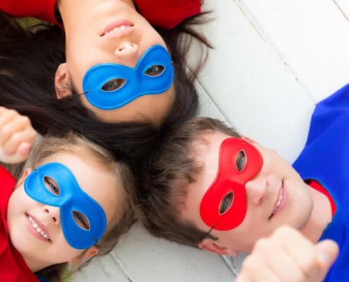 Family of three wearing superhero costumes, working on family financial goals