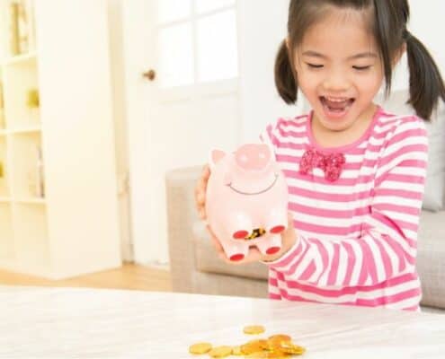 young child excitedly spilling her piggy bank contents onto table