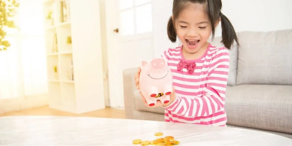 young child excitedly spilling her piggy bank contents onto table
