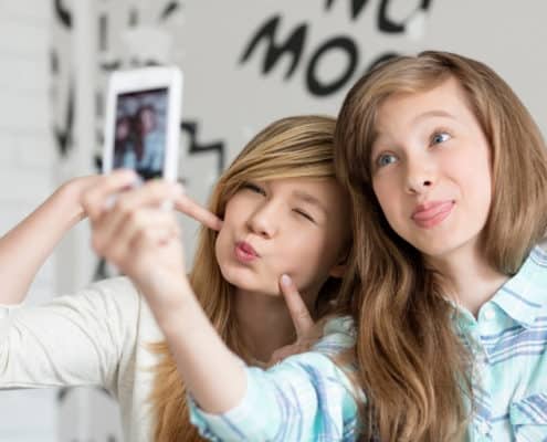 two teen girls taking a silly selfie on a phone
