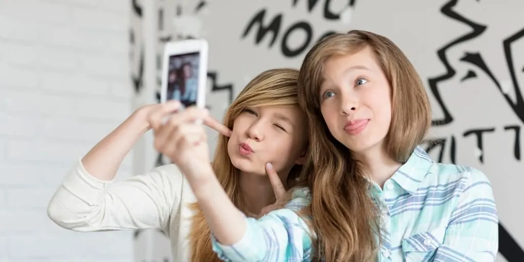 two teen girls taking a silly selfie on a phone