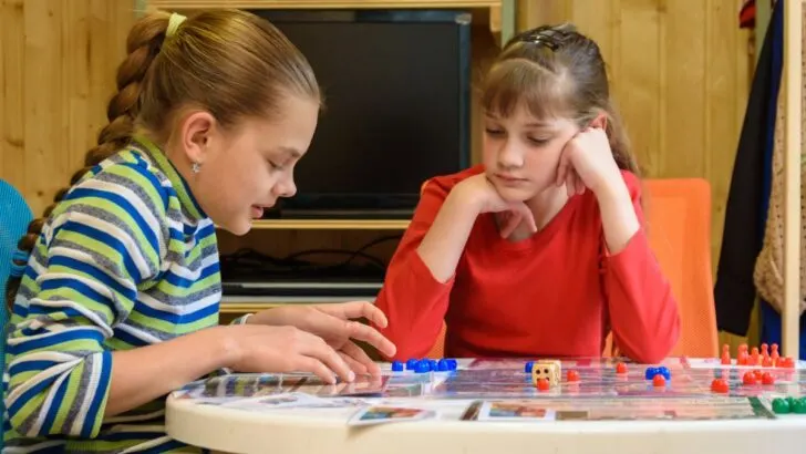 two girls playing money board game at home