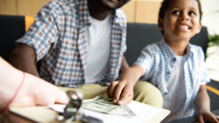 boy tipping waitress at restaurant with father