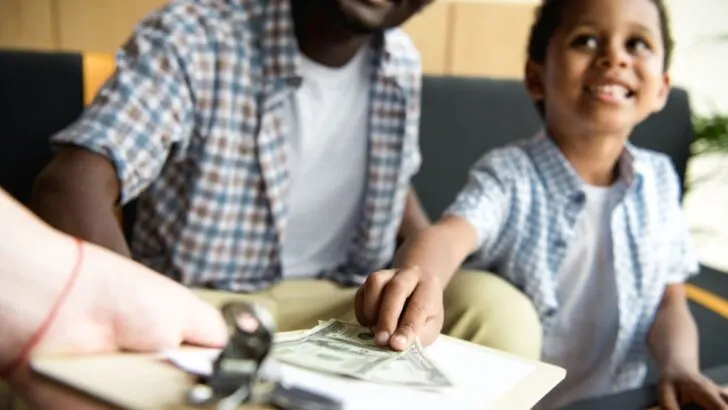 boy tipping waitress at restaurant with father