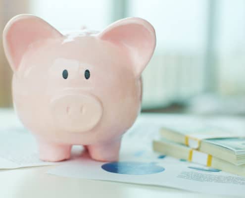 piggy bank with rolls of bills next to it