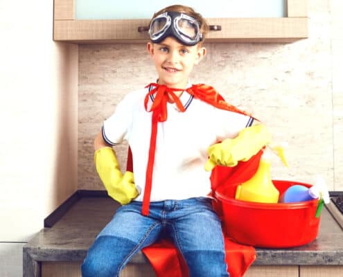 tween boy with superman cape, yellow gloves, bucket of cleaning supplies
