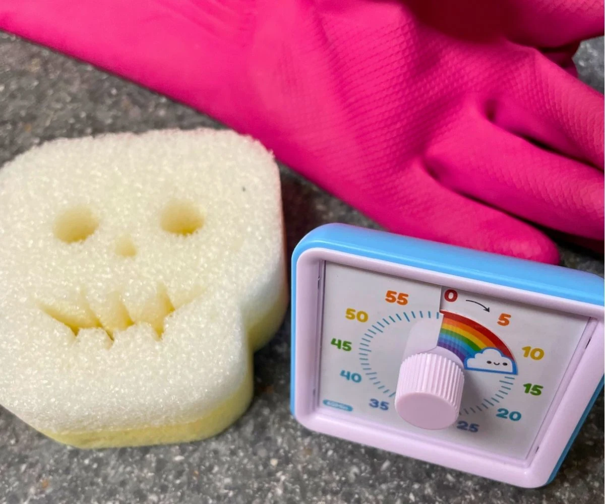 pink gloves, skull scrub daddy, and a rainbow timer showing 15 minutes