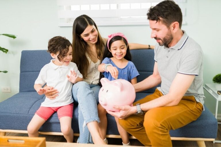 family sitting on sofa, father holding piggy bank and talking family money values