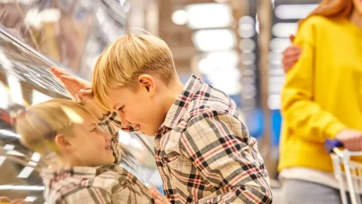 small boy looking in display case in grocery store wanting to buy it