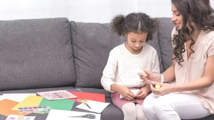 mother with young daughter, helping her glue together and make a vision board for kids