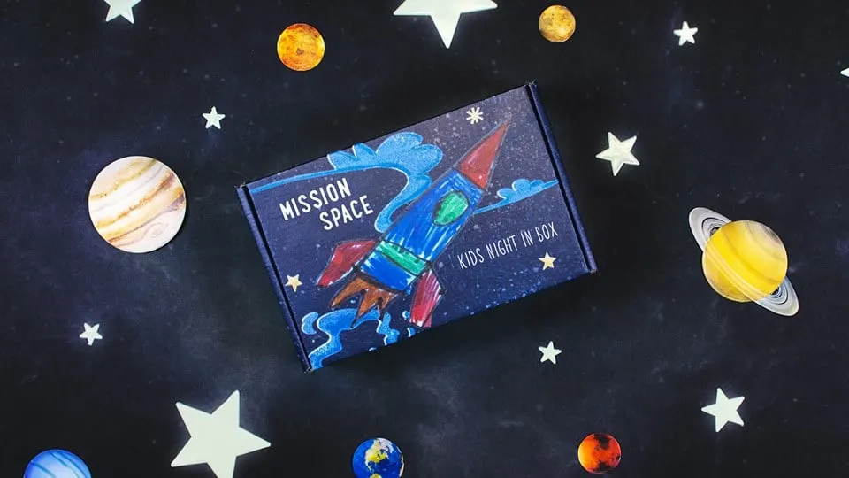 box with a rocket ship on it drawn by a kid, with stars and planets on background