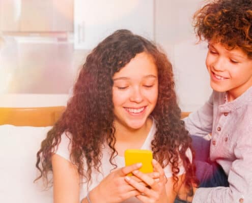 Two kids look at allowance chore apps on their phone with text overlay "what's the best chore app for kids?"