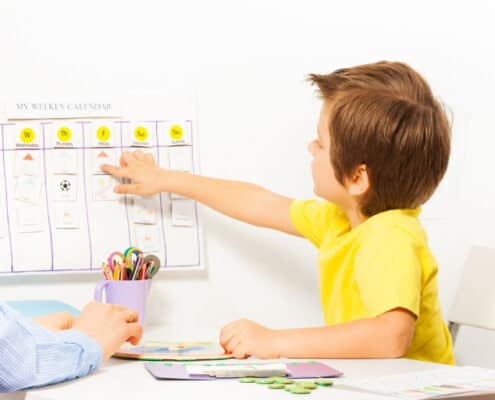 mother with child in yellow shirt, child pointing to chore chart for kid