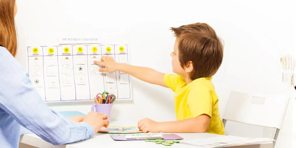 mother with child in yellow shirt, child pointing to chore chart for kid