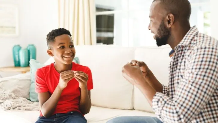 father using sign language with son on couch