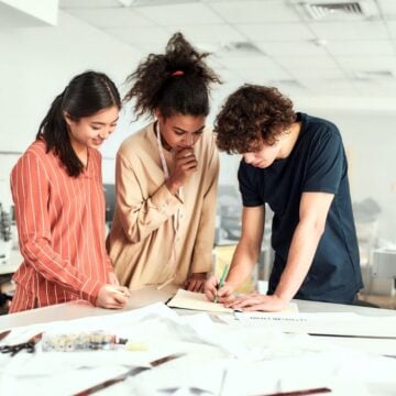 three teens working at a white table on something