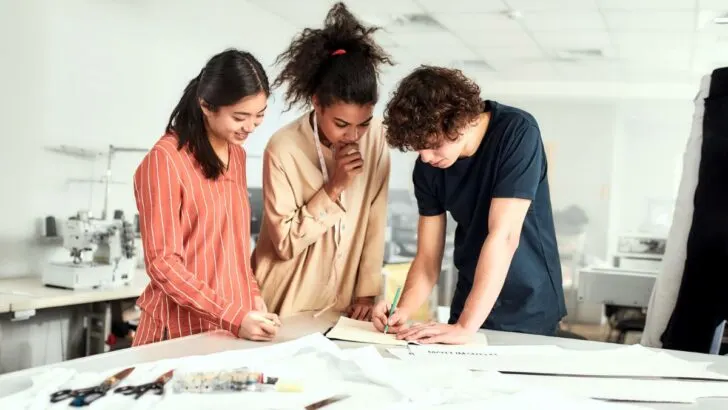 three teens working at a white table on something