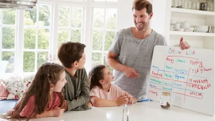 father with three kids giving out chores from their chore chart