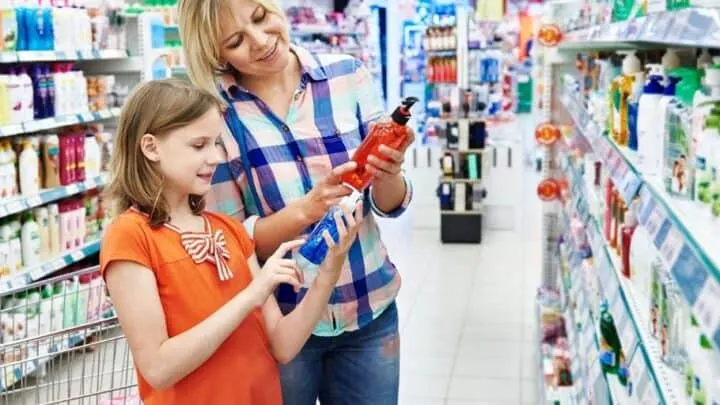 mother and daughter doing grocery store money challenge, looking at product bottles