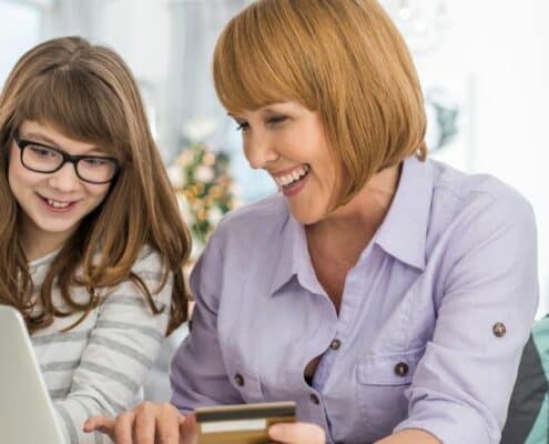 mother and daughter with glasses on laptop, making purchase with credit card