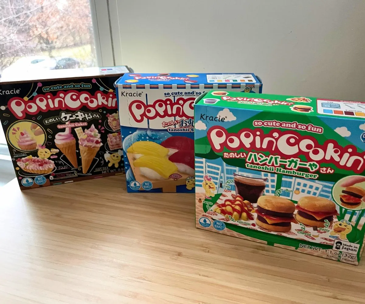 three colorful boxes of Popin' Cookin' mini candy art on a bamboo desk