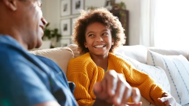 father and child laughing and talking on couch