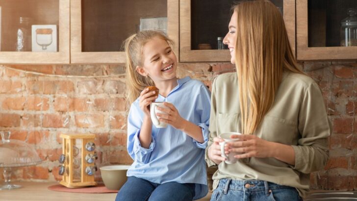 mother talking to daughter about money in kitchen, both smiling