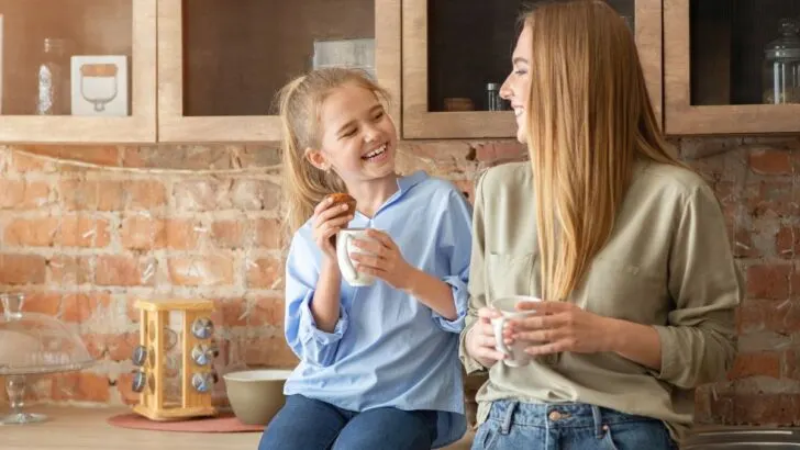 mother talking to daughter about money in kitchen, both smiling