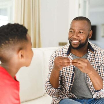 father using sign language to son on couch for learning money moment