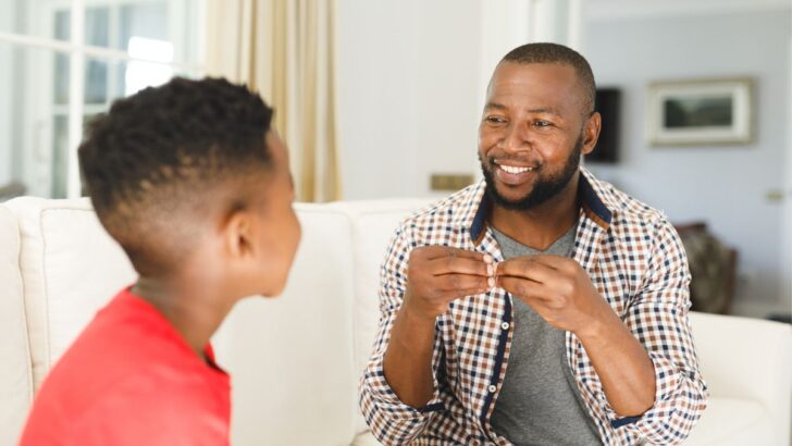 father using sign language to son on couch for learning money moment