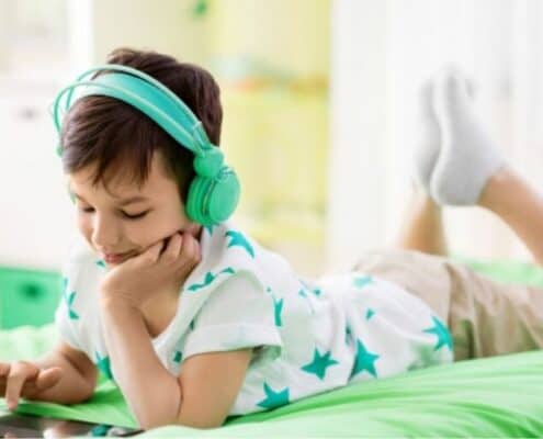 young boy laying on bed with iPad playing a math money app