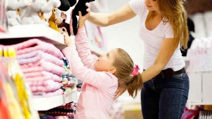 mom and daughter at store, daughter choosing something to buy