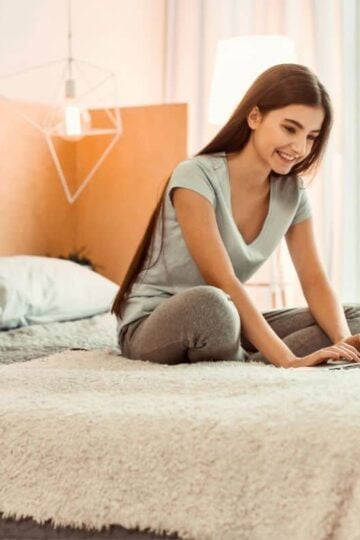girl teen on bed with laptop, smiling