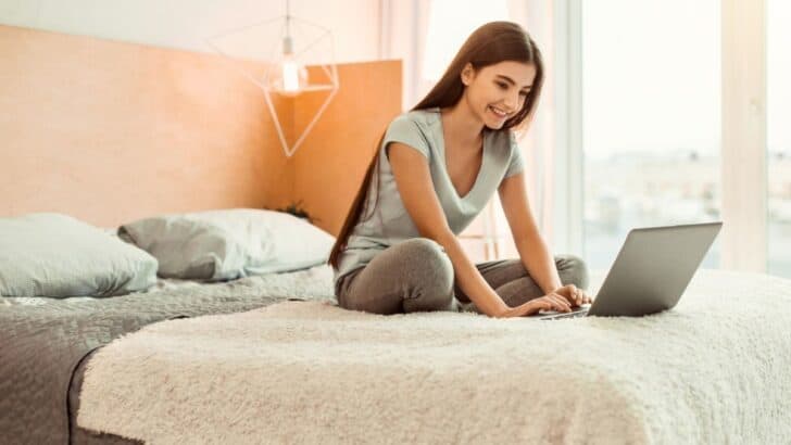 girl teen on bed with laptop, smiling