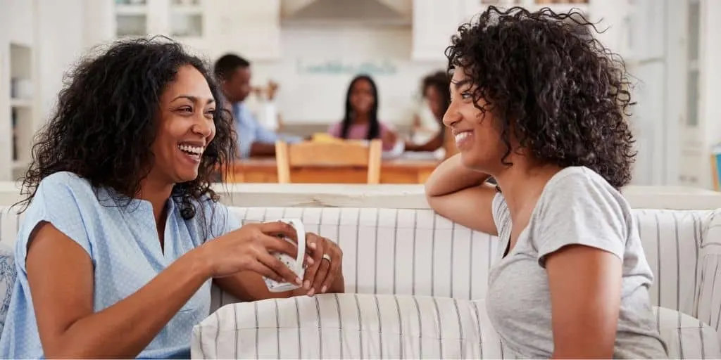 mother and daughter on couch, talking about first paycheck - teenager