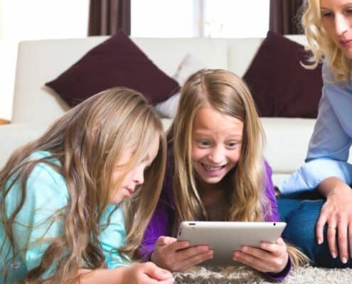 two kids with mother, sitting on floor excitedly learning about stock market
