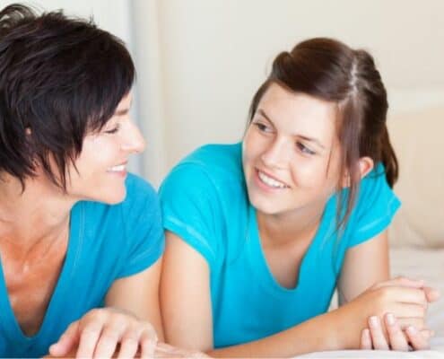 mother laying on bed, talking to her teenager through financial responsibility for teens