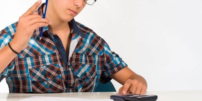 teen boy with calculator and pencil on desk filling in a budget worksheet for students