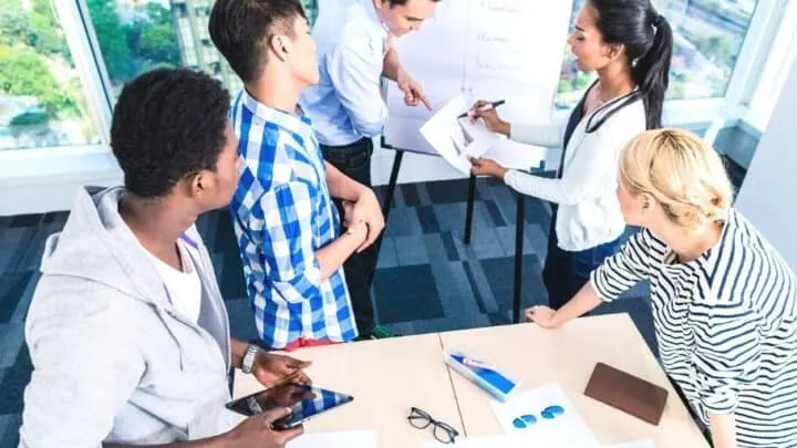 group of high school teens working on awards for young entrepreneurs with whiteboard