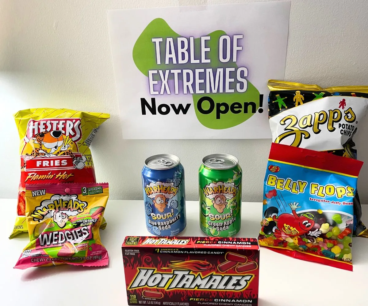 Table of Extremes funky green sign on wall above several hot and sour tasting products