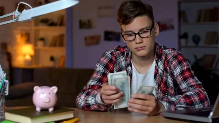 18 year old teen guy counting money at desk
