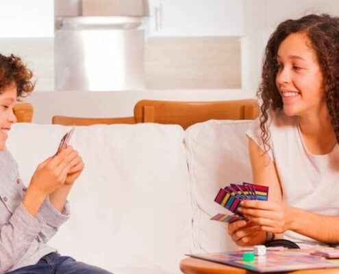 kids playing a fake money game together on the couch, smiling