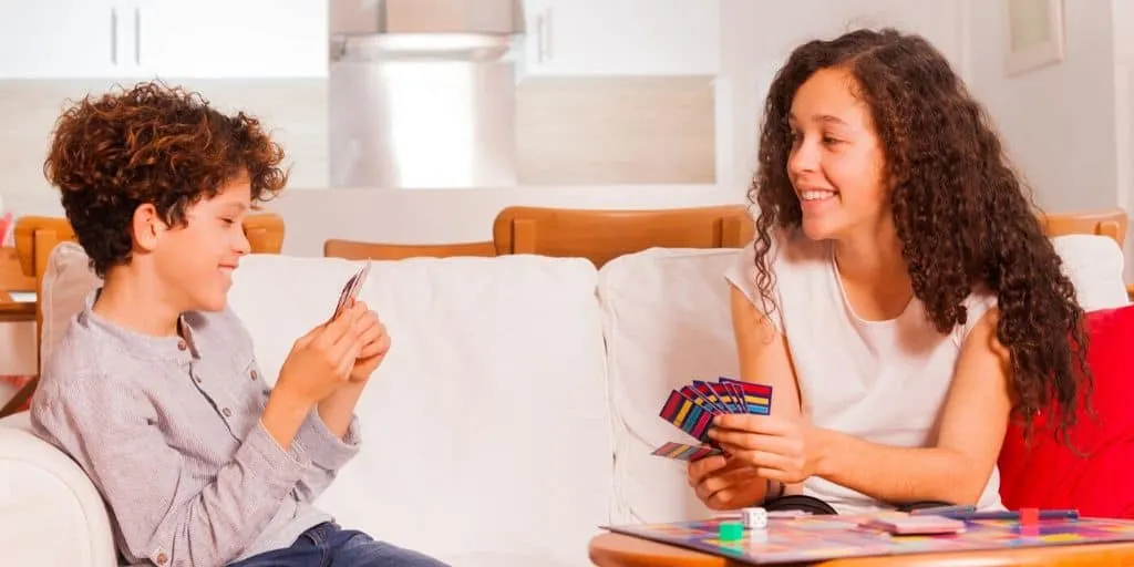 kids playing a fake money game together on the couch, smiling